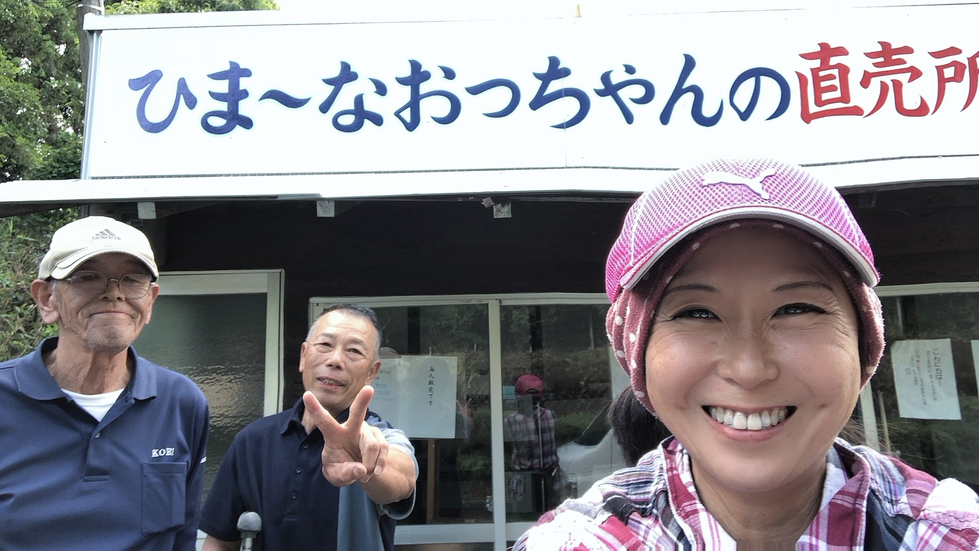 看板の前での自撮り。笑顔の農業女子とピースするおっちゃんたち